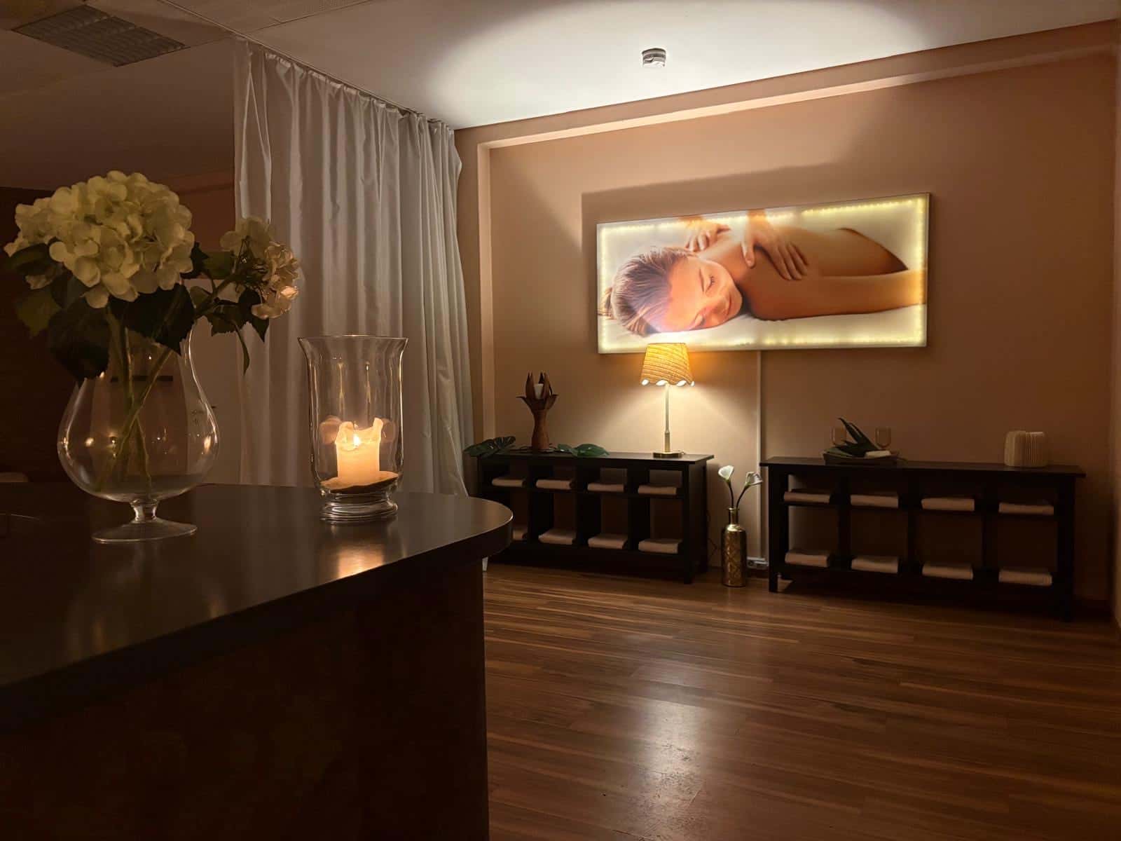 Reception of the massage studio at Jacobstraße 5 with candle, flowers and illuminated wall picture