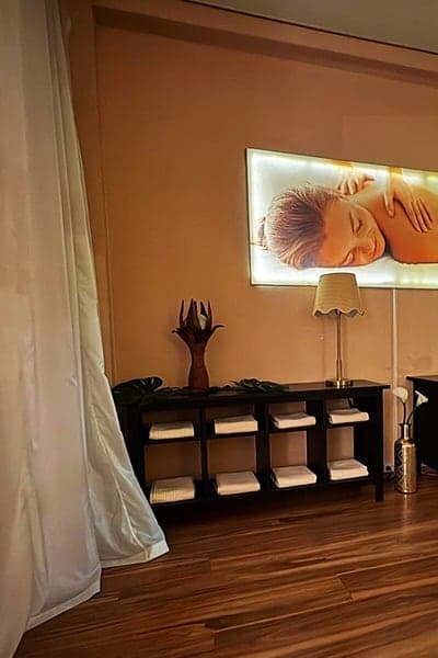 Behandlungsraum mit Massageliege, Handtüchern und warmem Licht