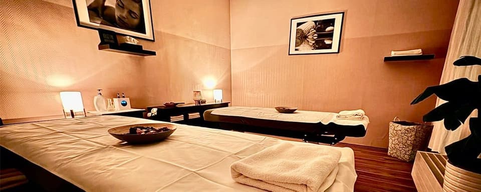 Doppelraum im Studio mit zwei vorbereiteten Massageliegen und warmem Licht